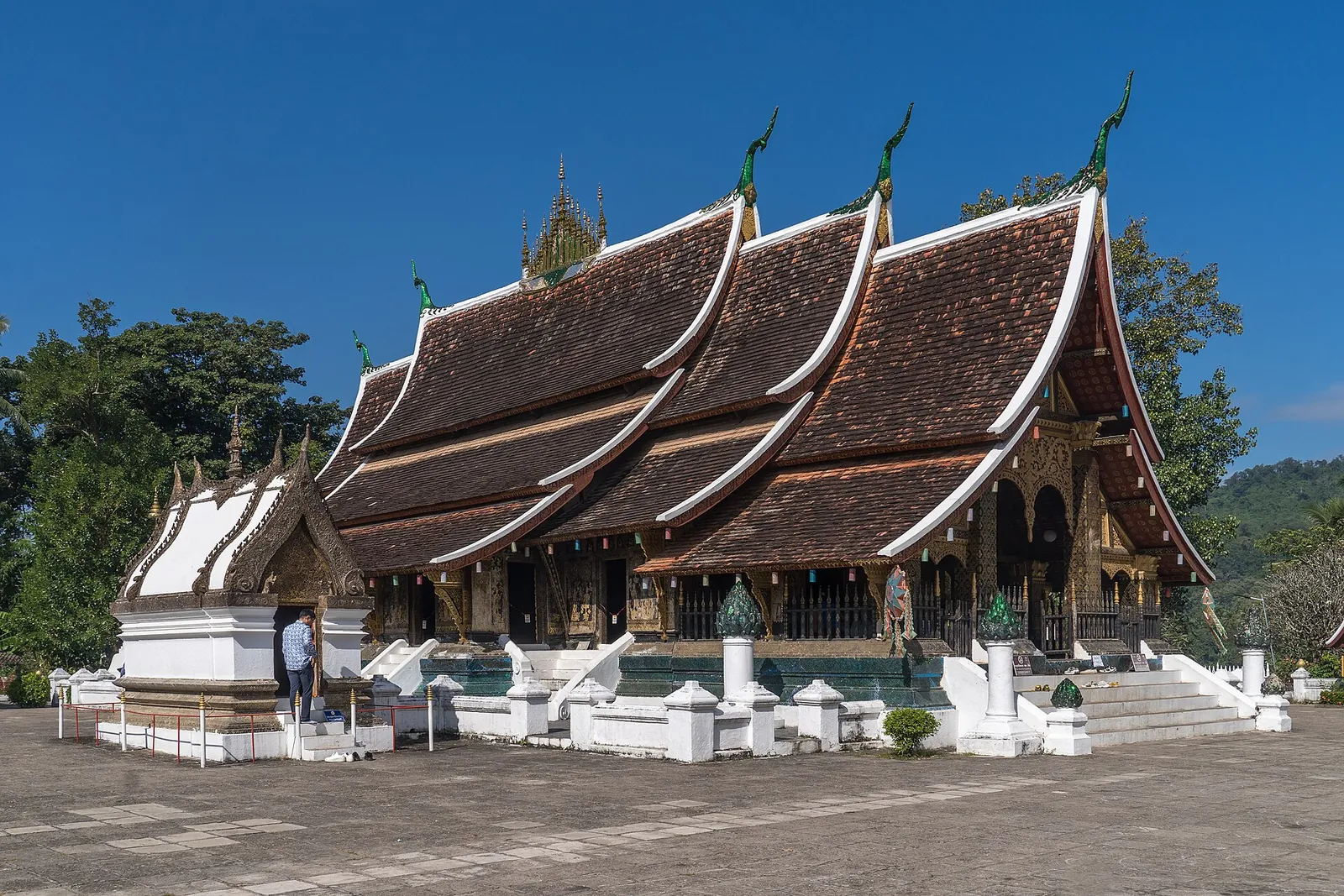 The sweeping tiered roofs of Wat Xieng Thong in Luang Prabang under a blue sky
