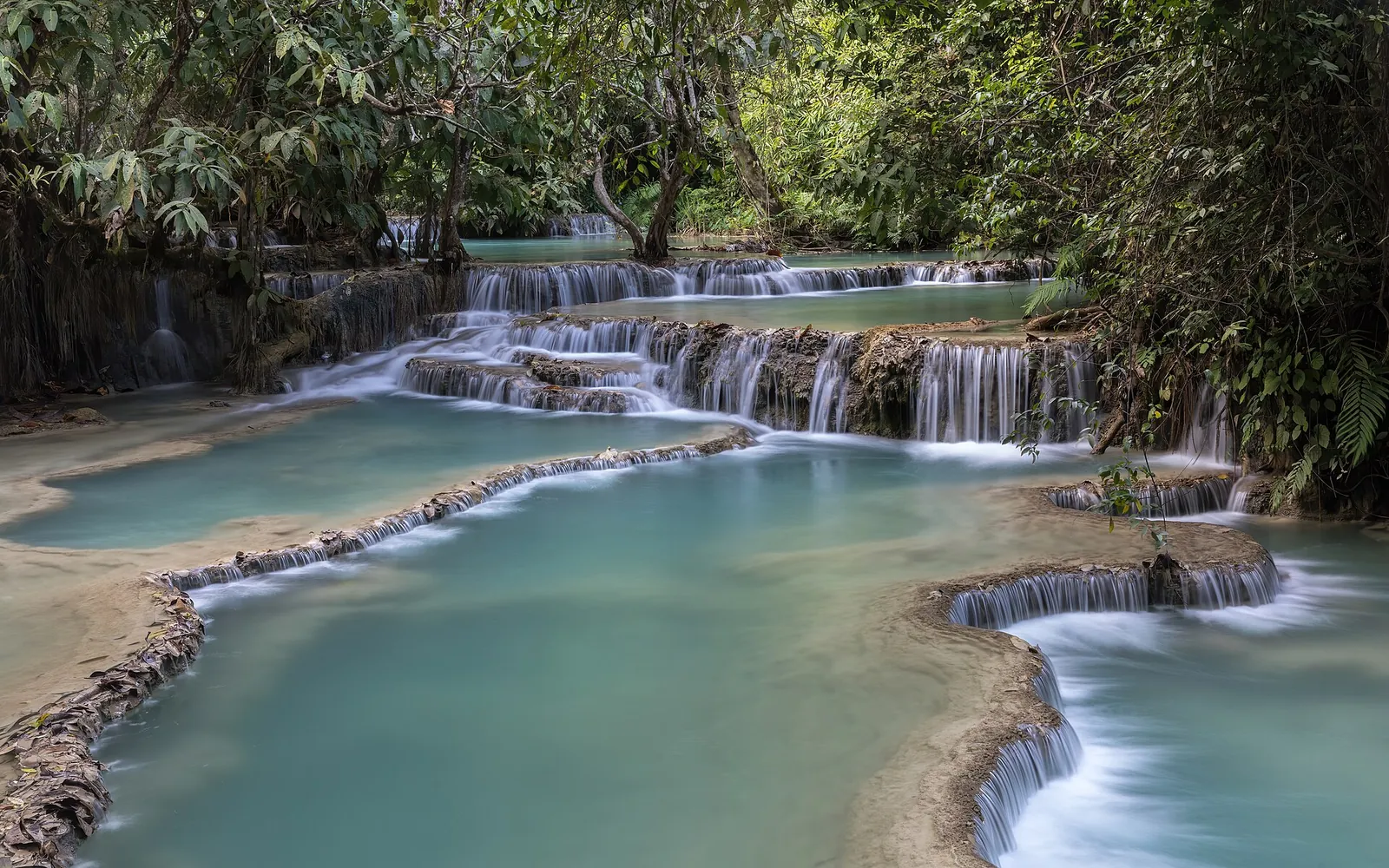 Turquoise tiered pools at Kuang Si Falls in the forest