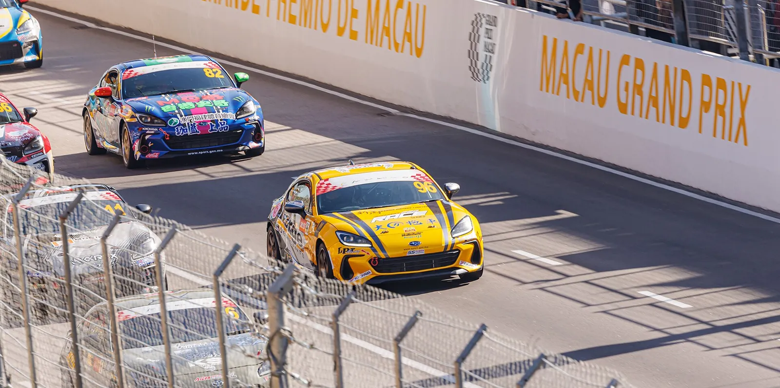 Racing cars passing the barrier wall on the Guia street circuit during the Macau Grand Prix