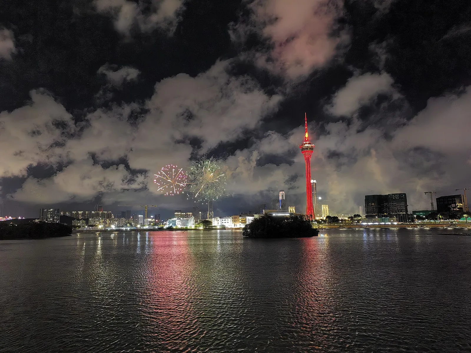 Fireworks bursting over the water with Macau Tower lit up behind