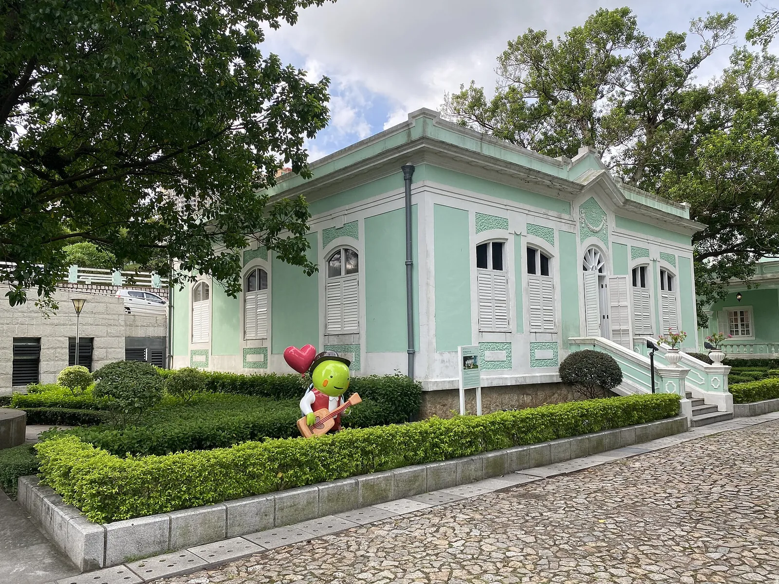 Zelený dům v Taipa Houses vedle kamenné dlážděné cesty