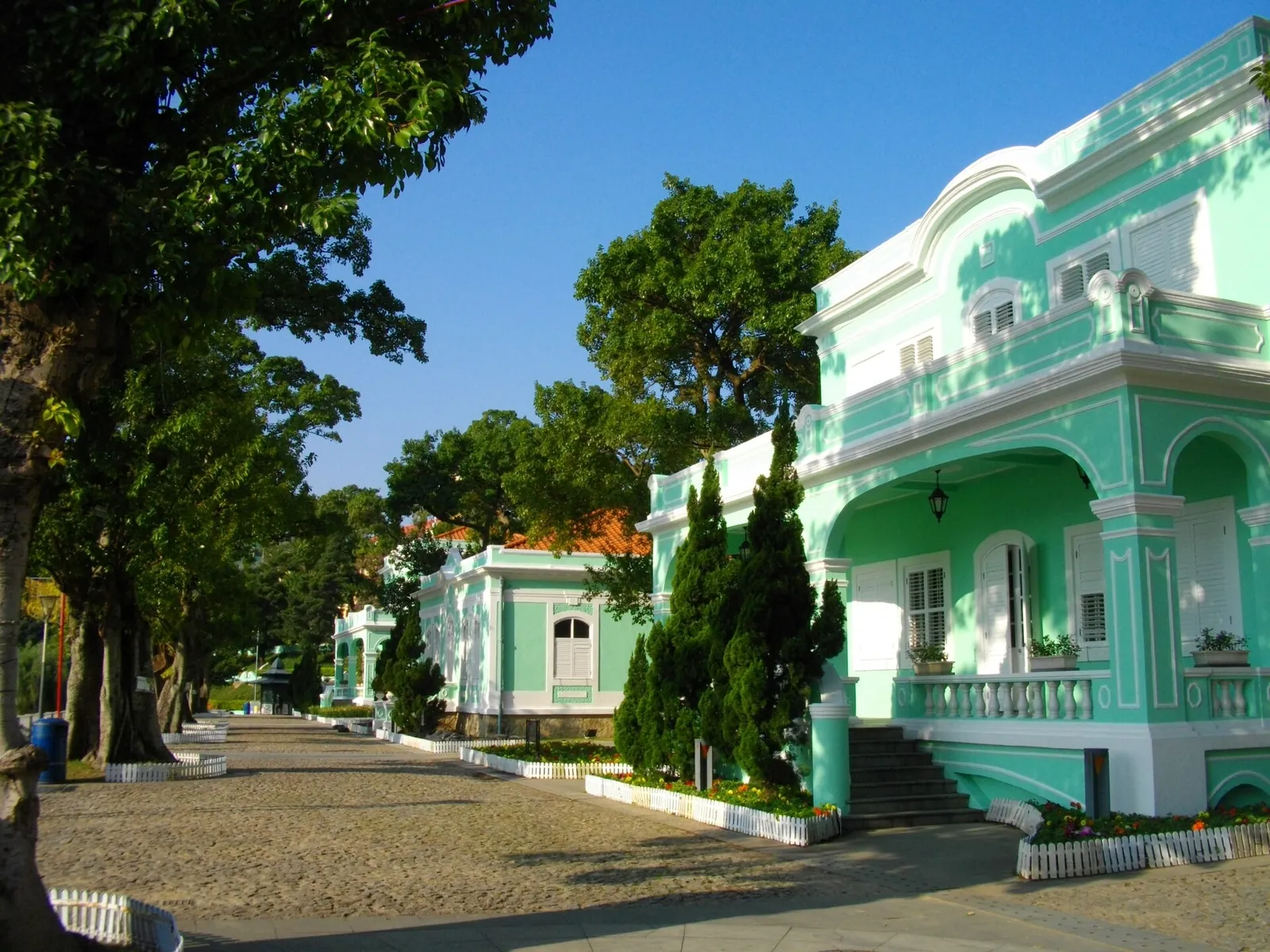Zelené Taipa Houses vedle stinné dlážděné cesty