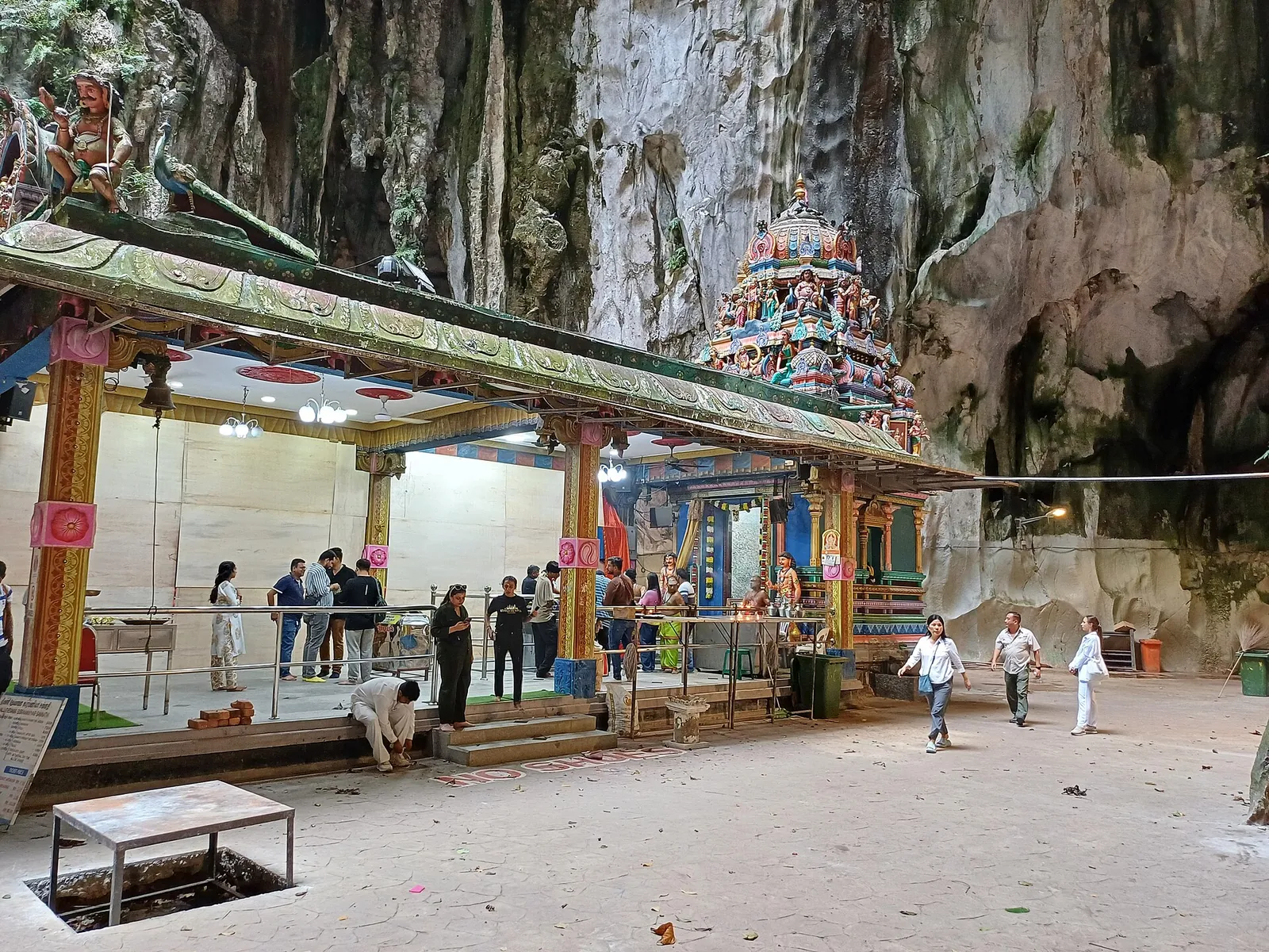 Colourful Hindu shrines beneath the high limestone walls inside Temple Cave at Batu Caves