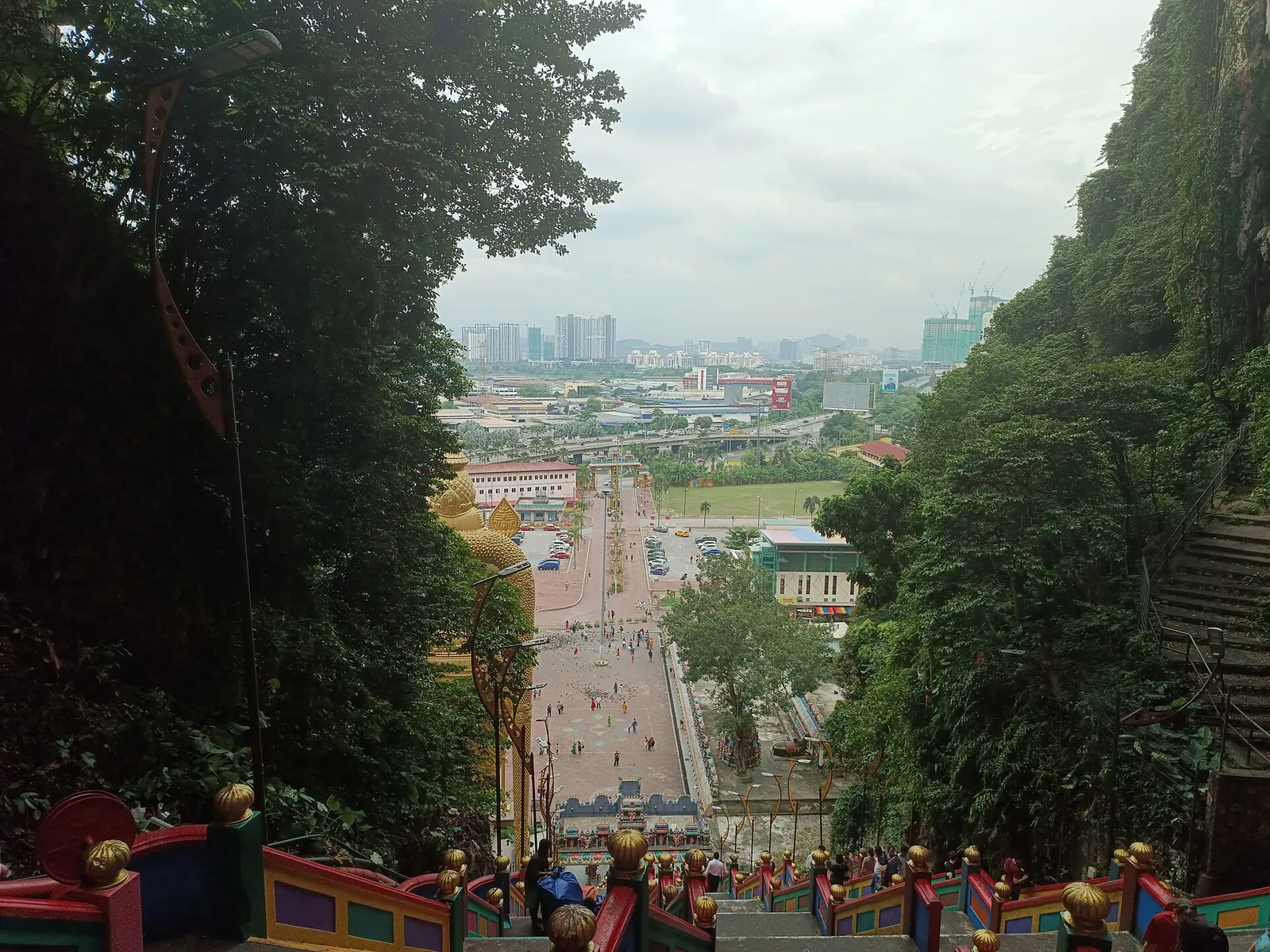 View down the Batu Caves stairs toward the forecourt and distant city buildings