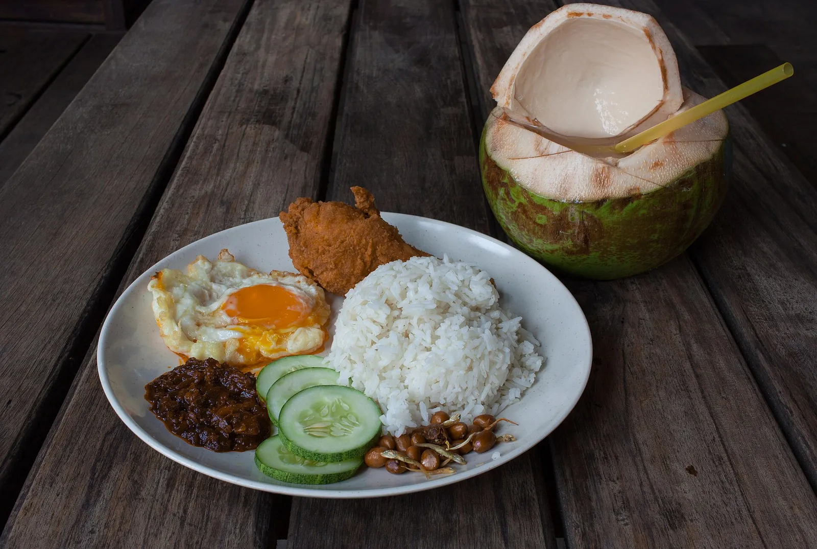 Tallerken med nasi lemak, æg, sambal og en frisk kokosnød