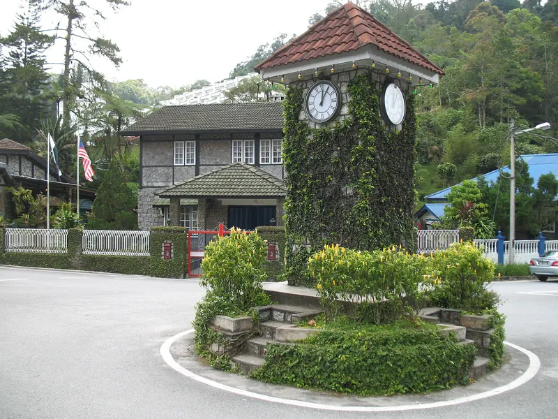 Stone clock tower on a small roundabout in the wooded center of Frasers Hill