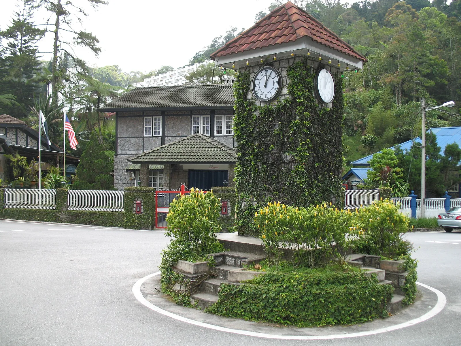Stone clock tower on a small roundabout in the wooded center of Frasers Hill