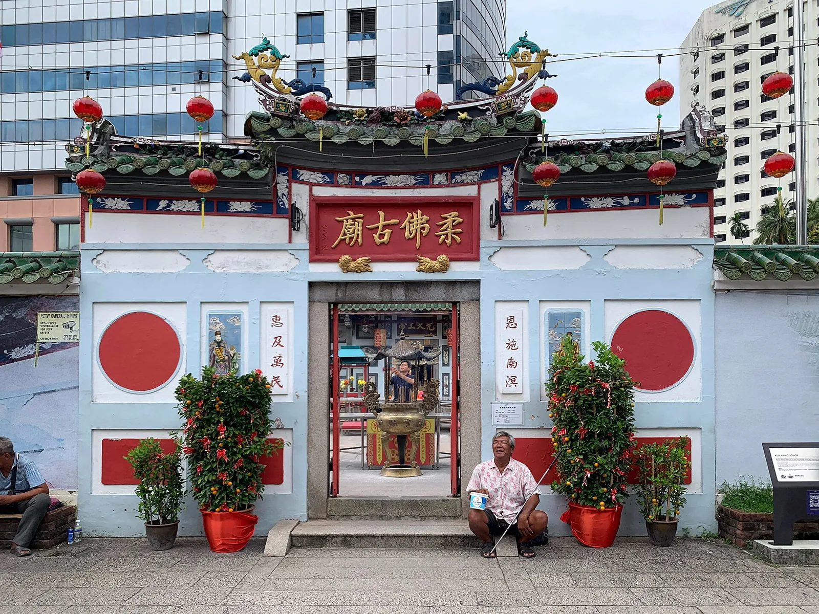 Red and white entrance of the Old Chinese Temple among city buildings in Johor Bahru