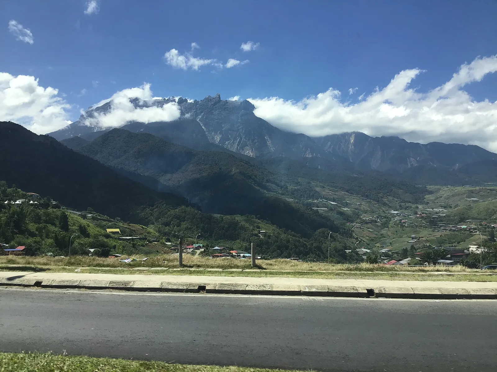 Mount Kinabalu ponad zielonymi stokami i polami doliny Kundasang