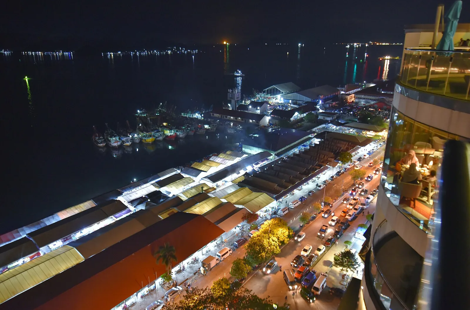 Illuminated waterfront market and coastal buildings in Kota Kinabalu at night