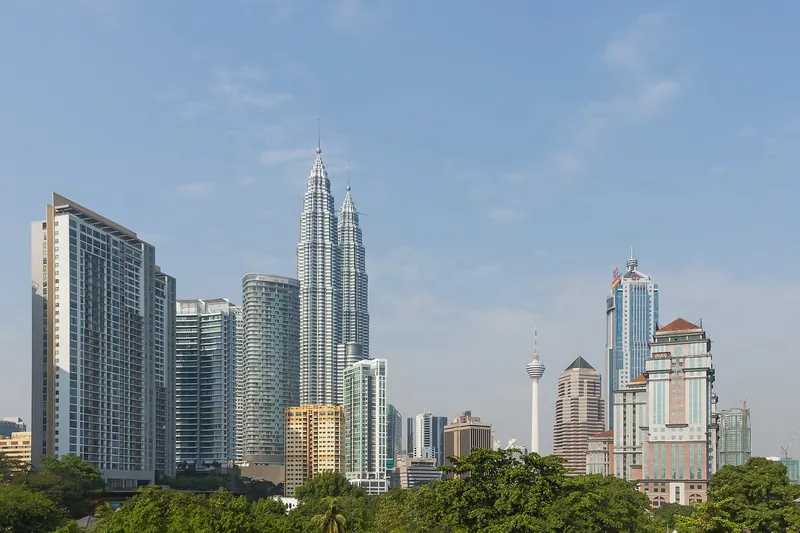 Petronas Twin Towers and central Kuala Lumpur buildings above green trees