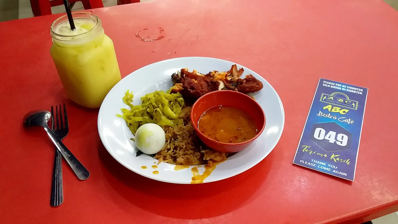 Nasi lemak with chicken and accompaniments on a cafe table in Brickfields