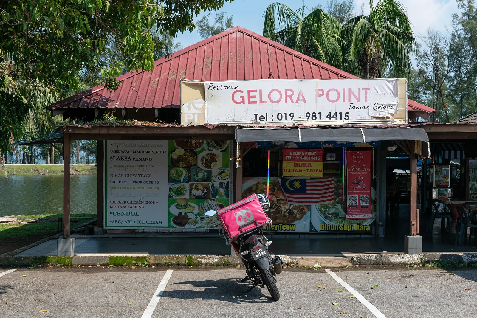 Red-roofed restaurant beneath palm trees at Taman Gelora in Kuantan