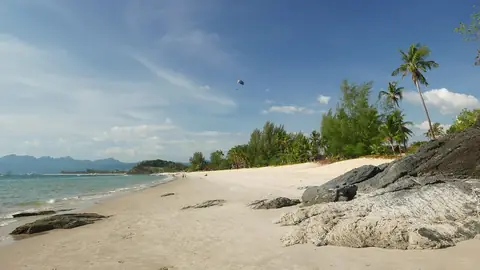 Palmer, hvidt sand og blåt vand ved Pantai Cenang i Langkawi