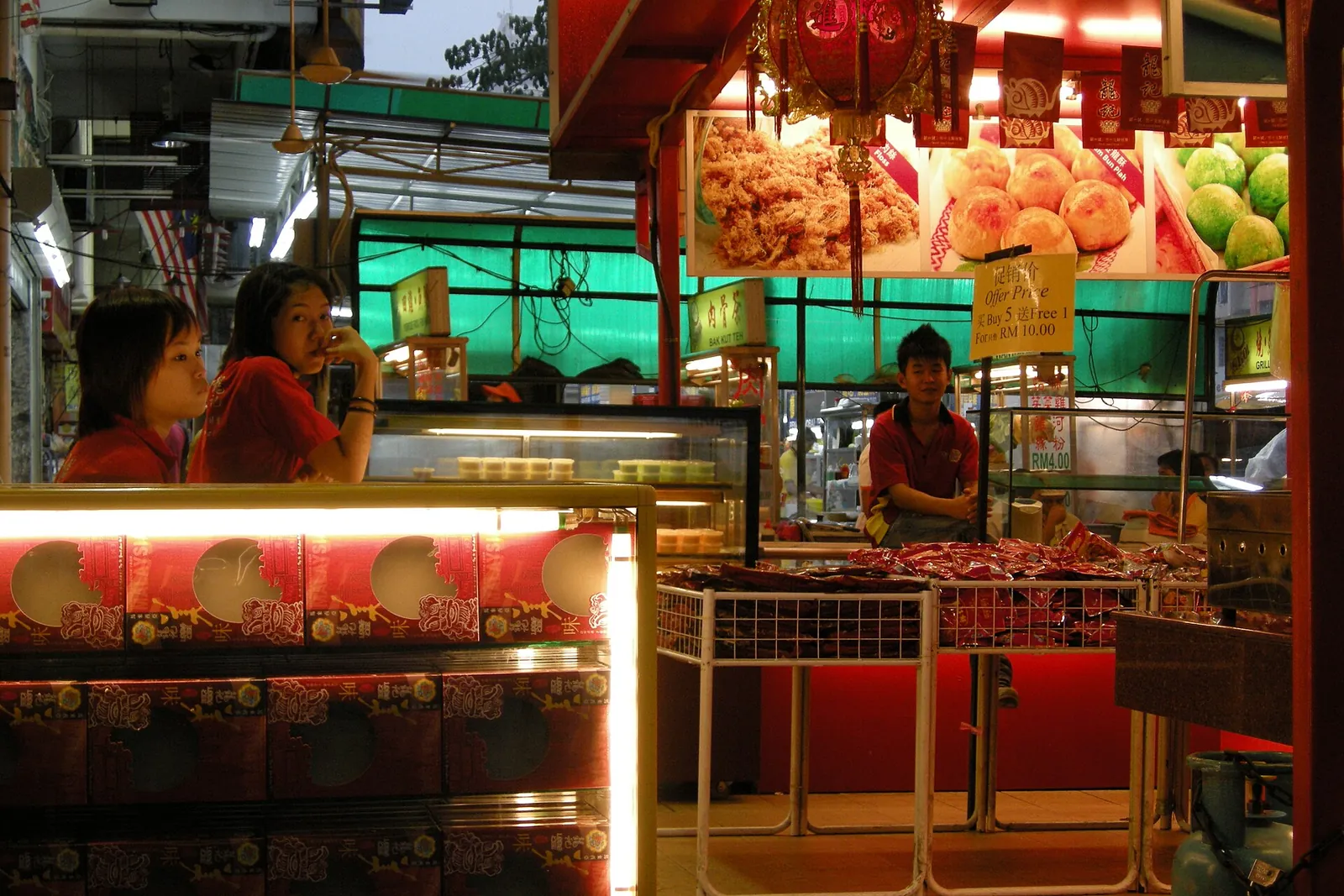 Lit food stalls and menu photographs in a Bukit Bintang food court in Kuala Lumpur