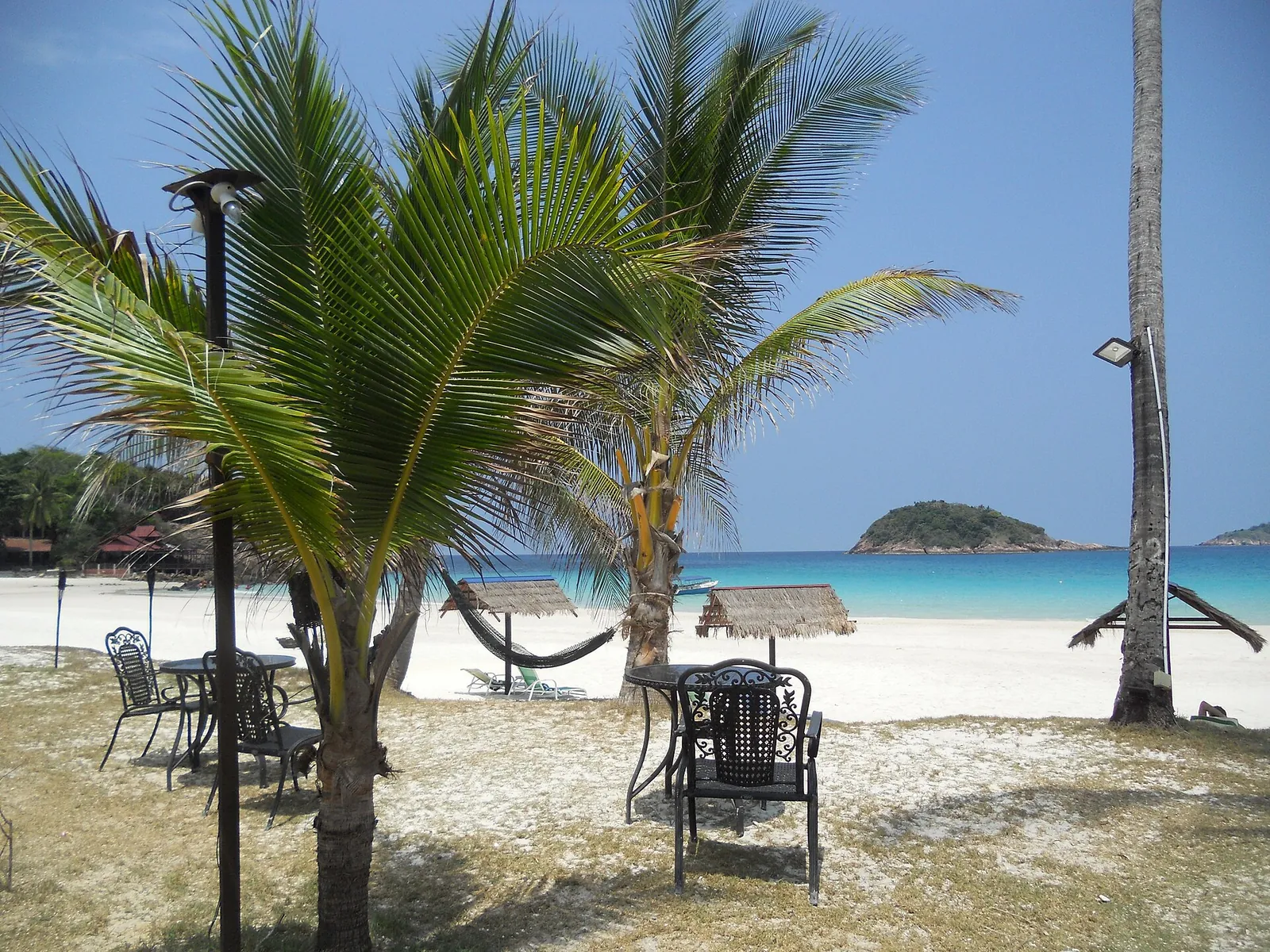 Palm trees, beach chairs and pale sand facing turquoise water on Redang Island