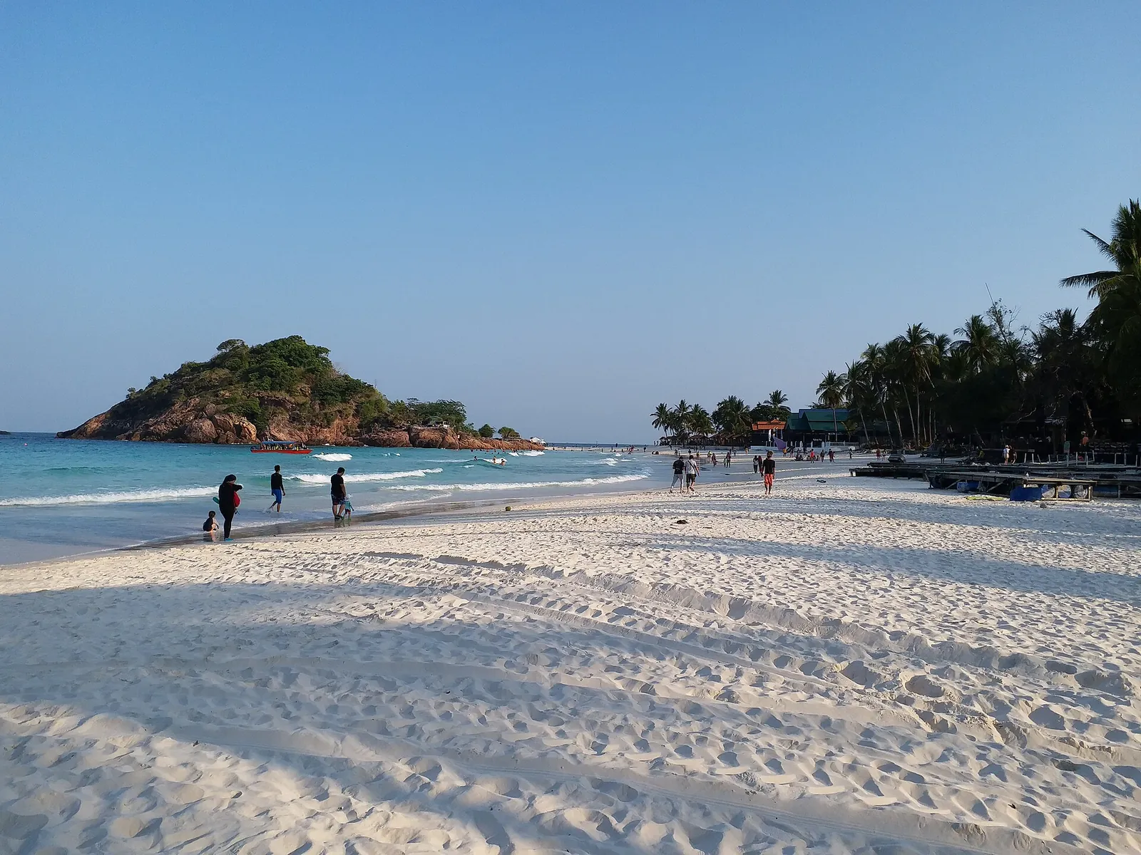 Visitors walking across broad white sand beside the sea on Pulau Redang
