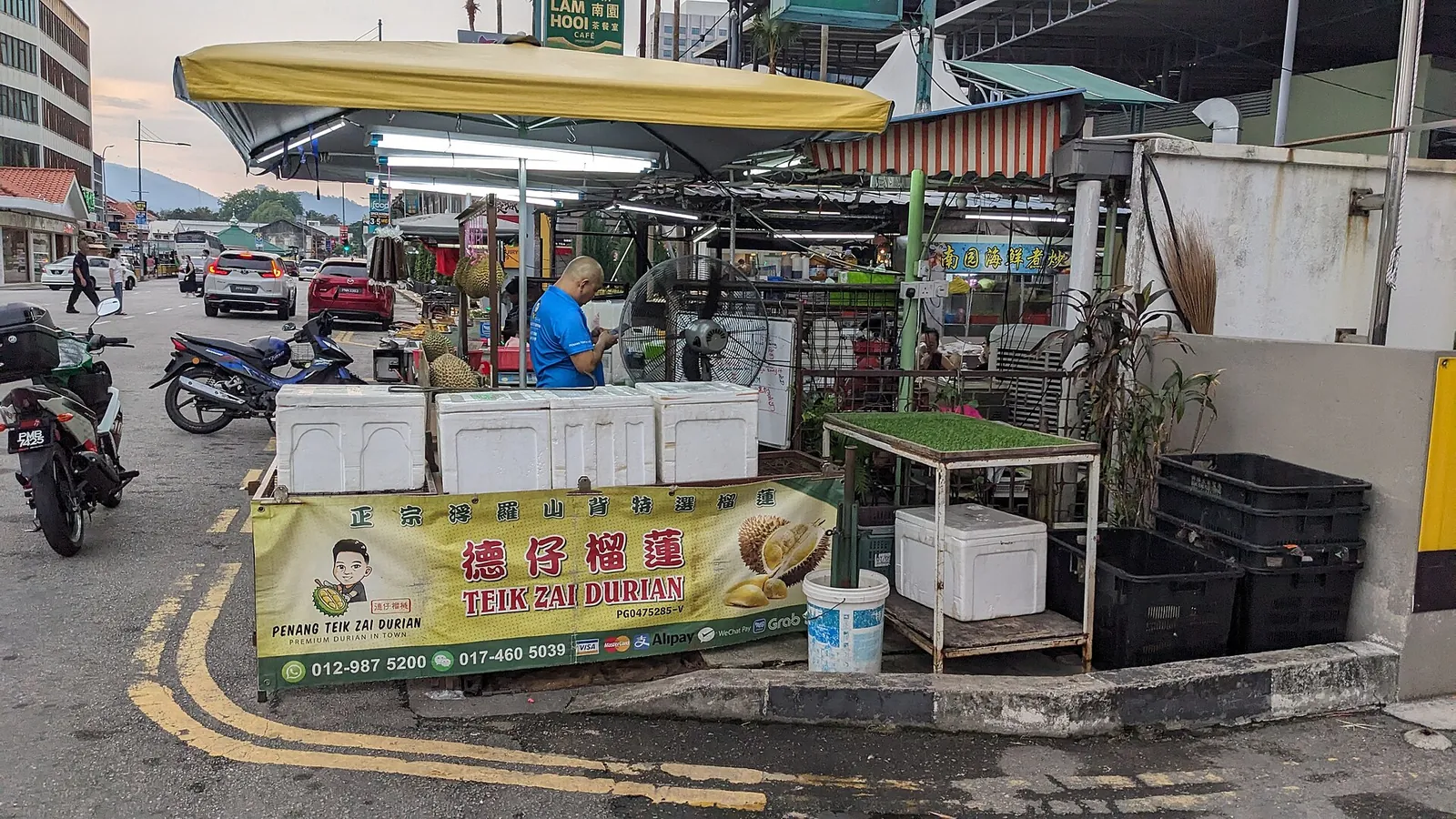 A hawker stall market on Jalan Burma in George Town with tables and parked motorbikes