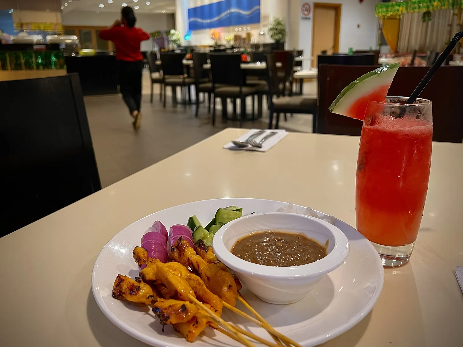 Satay skewers with sauce and a drink on a table in Melaka