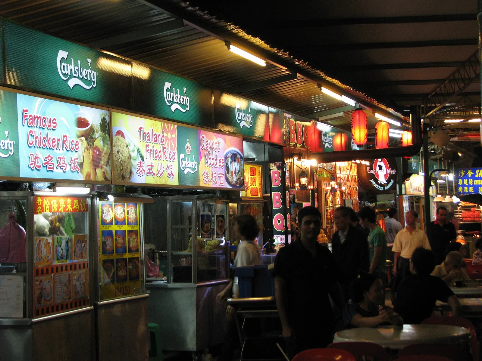 Illuminated stalls and customers at a Penang food court in the evening