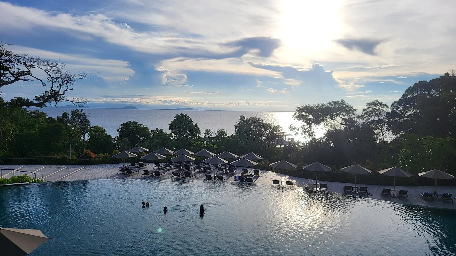 Sunset sky above waterfront buildings and swimmers on Perhentian Kecil