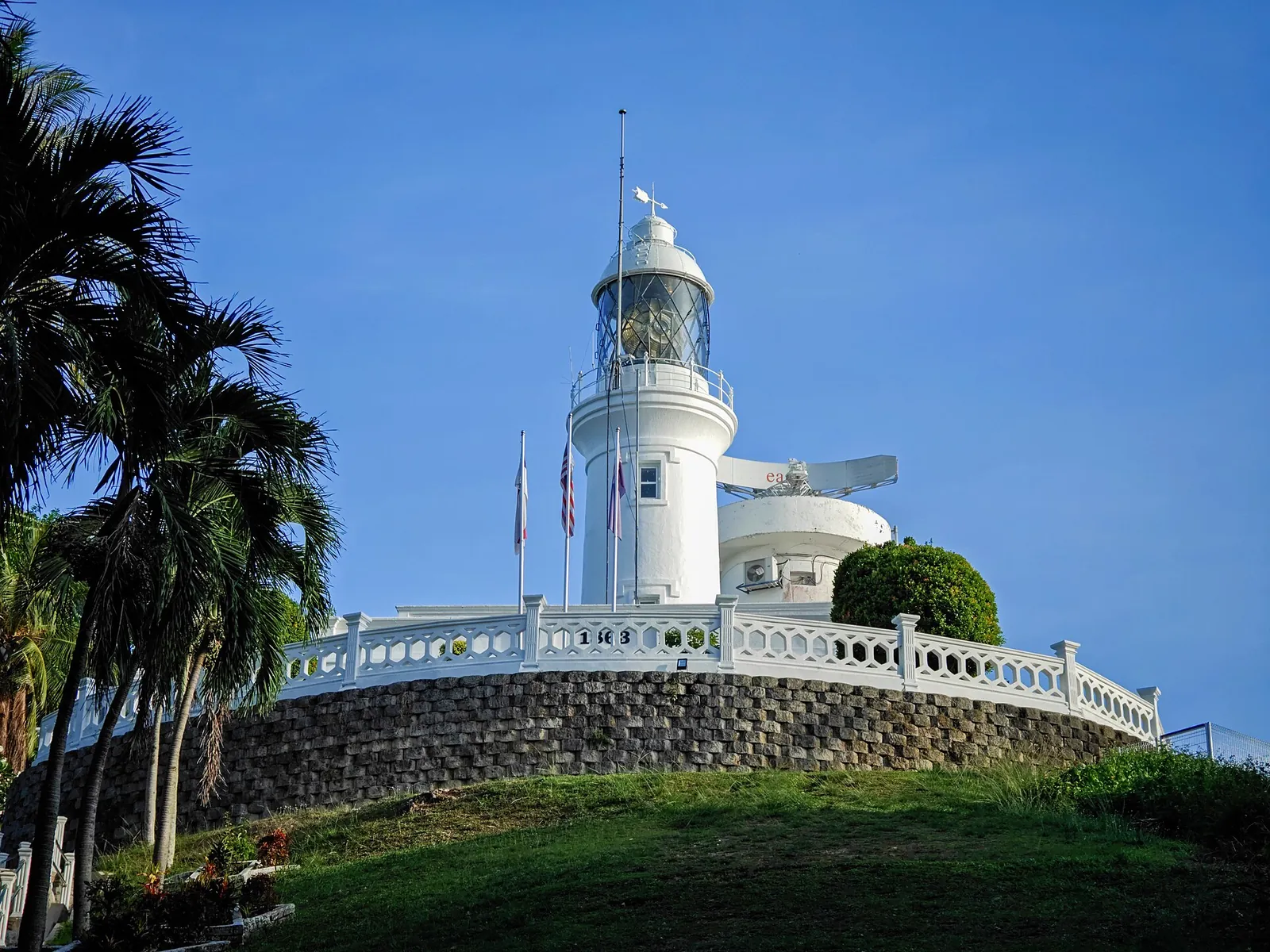 White Cape Rachado lighthouse on a green hill beneath a blue sky