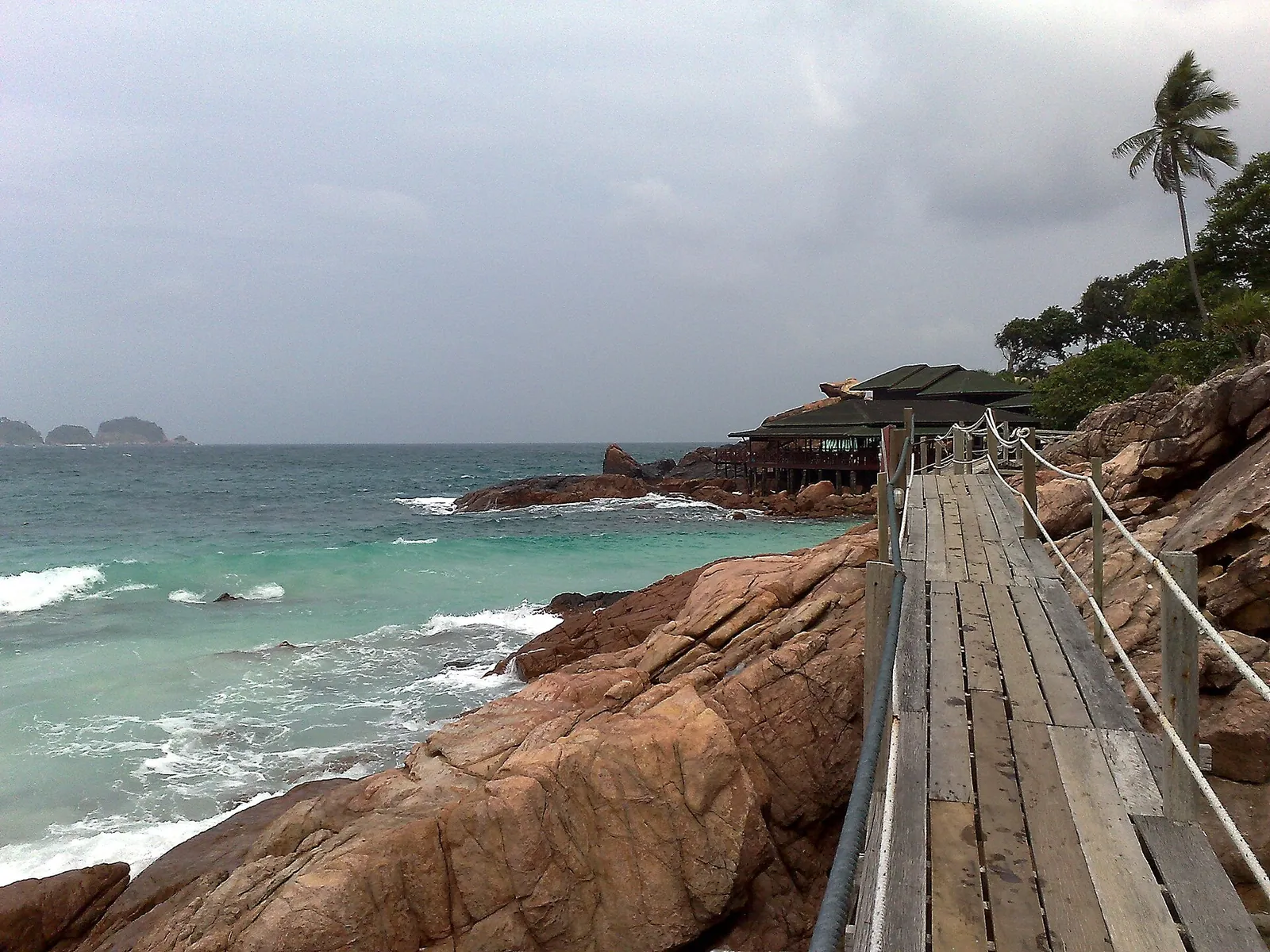 Wooden walkway beside rocky shore and turquoise sea on Redang Island