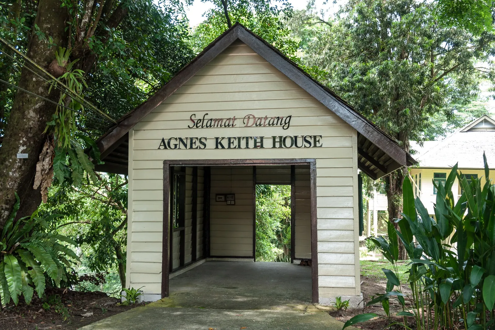 Agnes Keith House entrance sign among green trees in Sandakan