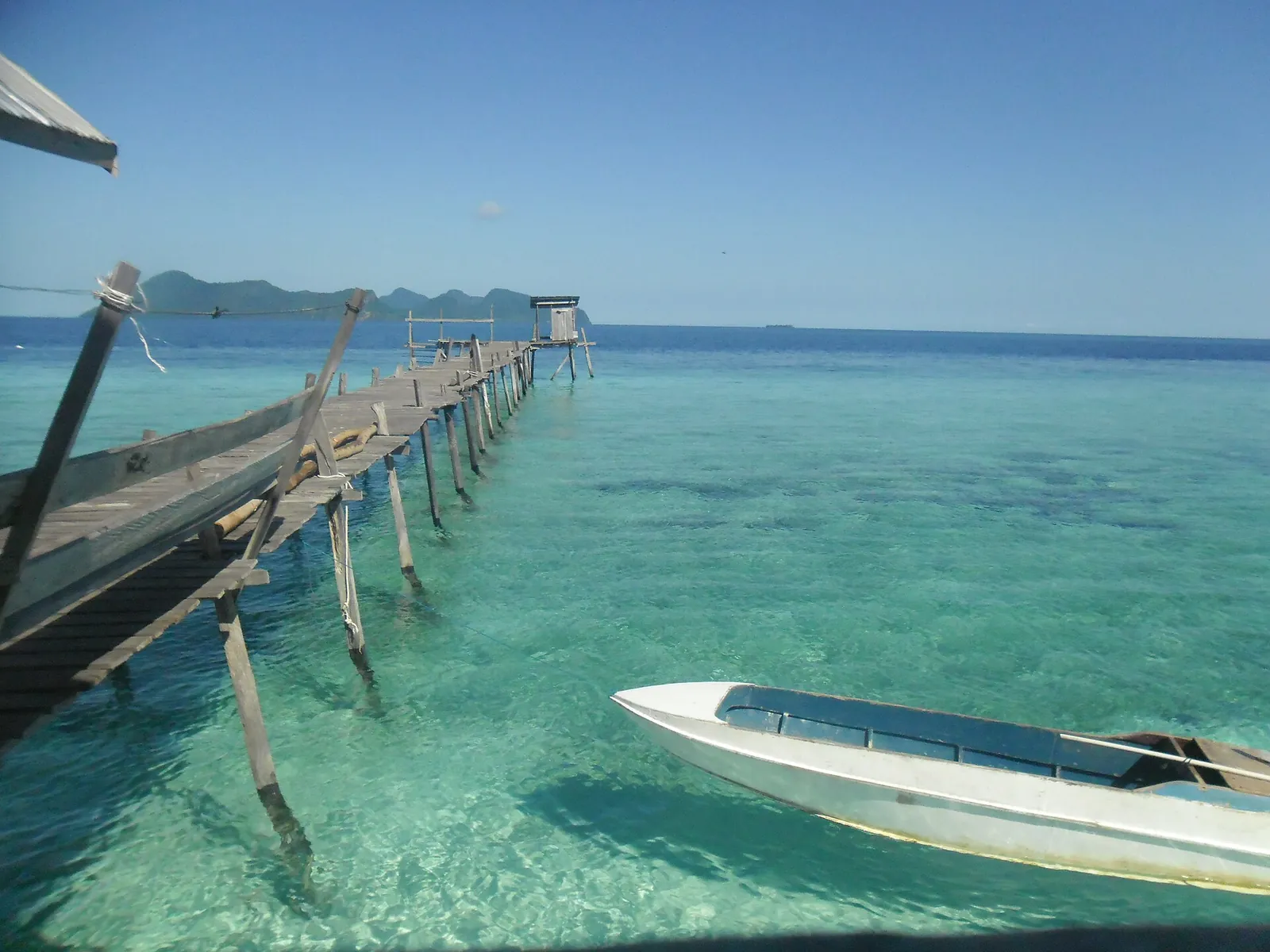 A jetty and boats above clear turquoise water at Pom Pom Island