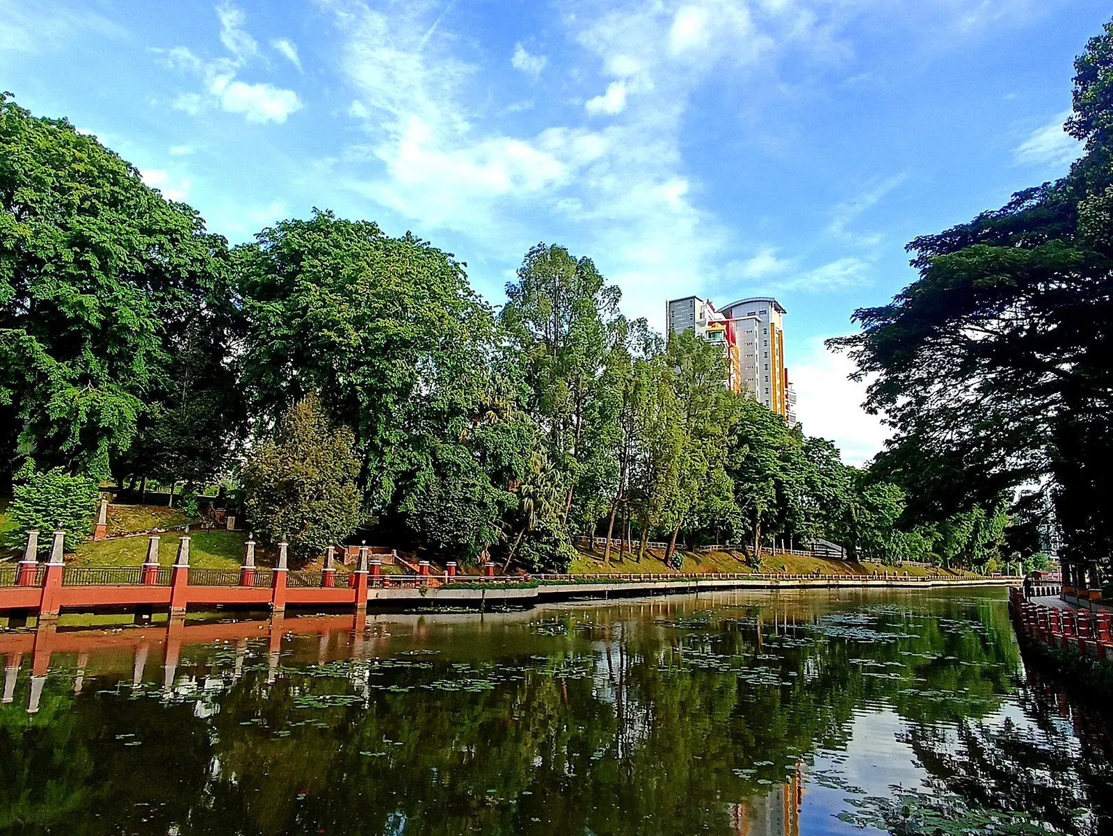 Trees and lakeside structures reflected in the water at Seremban Lake Gardens