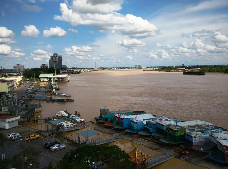 Boats beside the broad Rajang River and Sibu waterfront under a blue sky