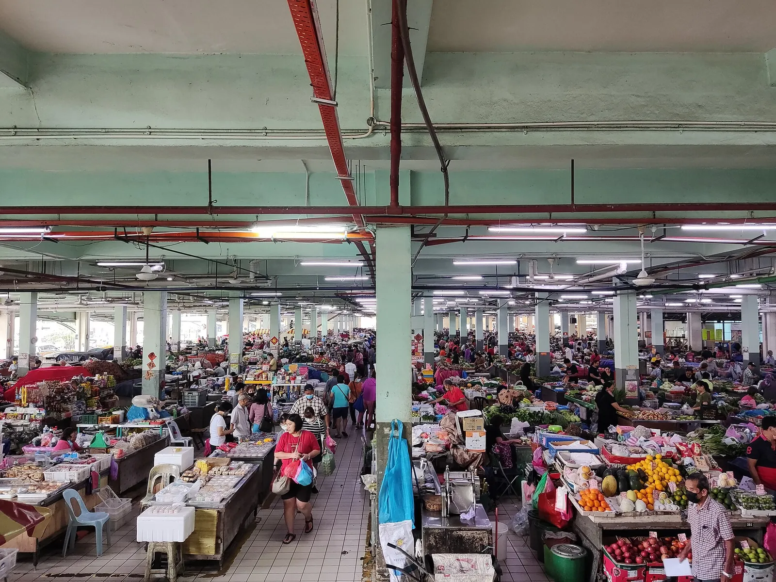 Rows of produce stalls and shoppers inside Sibu Central Market