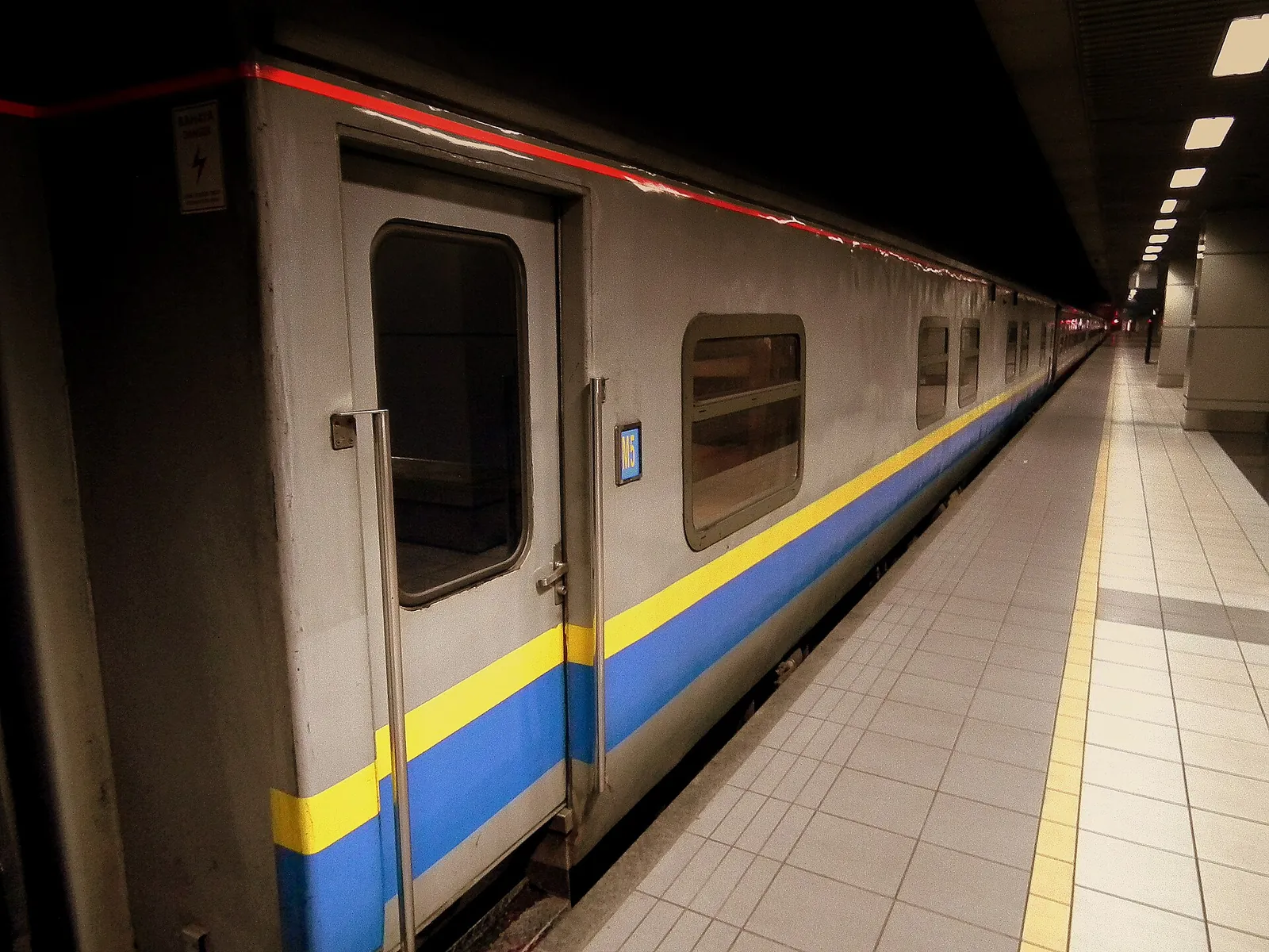 A Malaysian passenger train beside a lit platform at KL Sentral at night