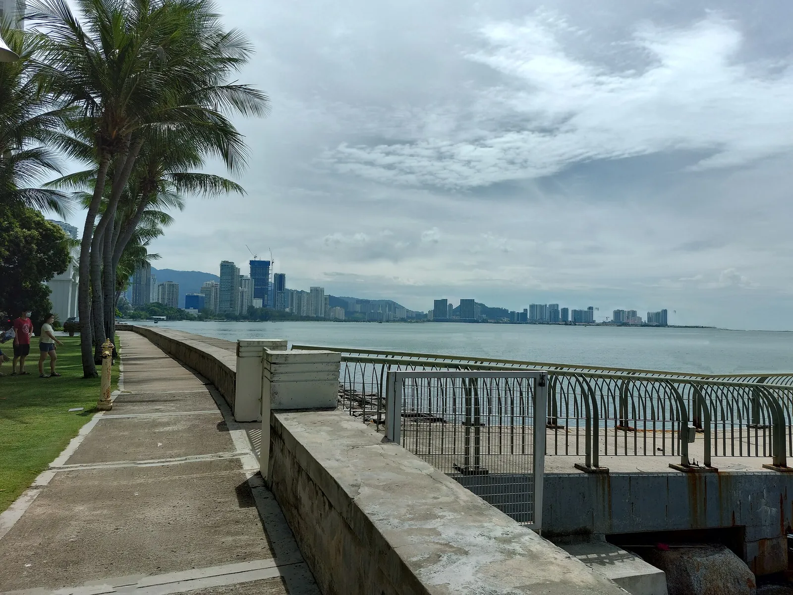 Palm-lined waterfront path facing the northern George Town skyline
