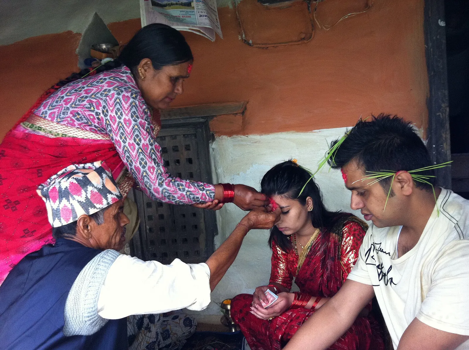 Una mujer mayor coloca tika roja en la frente de una joven durante Dashain