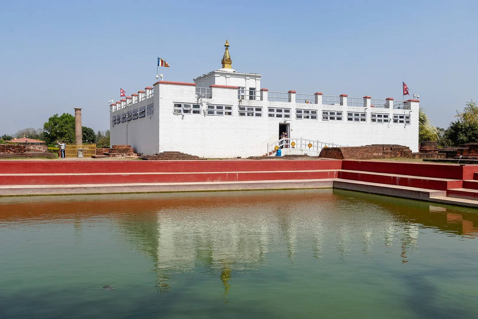 The white Maya Devi Temple reflected in the sacred pond under a clear sky at Lumbini