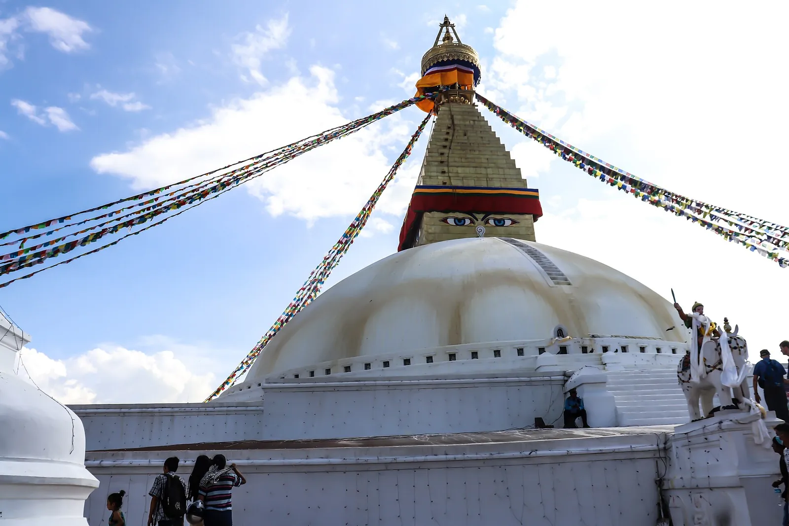 The white dome and prayer flags of Boudhanath stupa under a blue sky