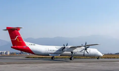 Un Dash 8-400 de Shree Airlines despegando del aeropuerto internacional Tribhuvan con colinas al fondo