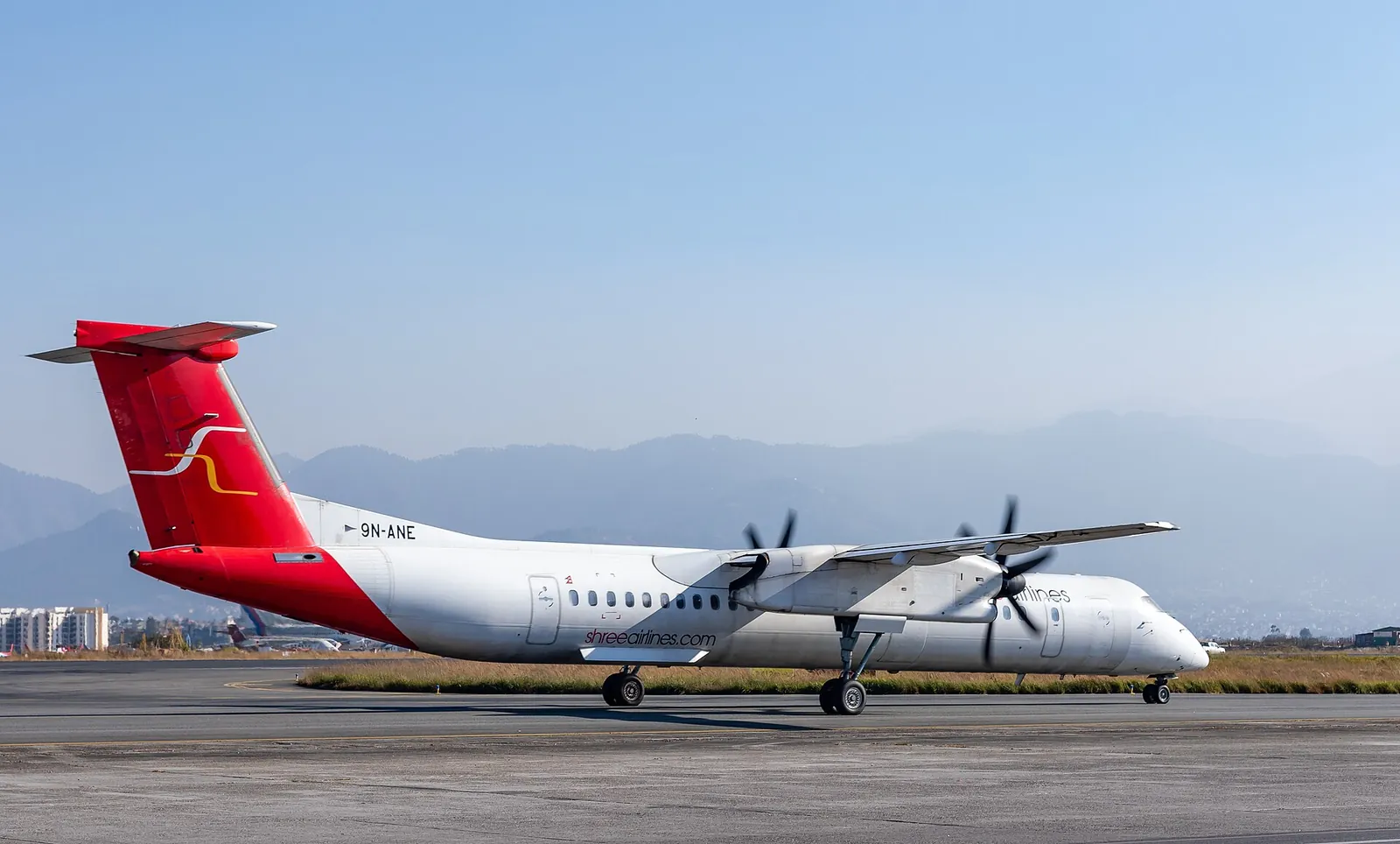 Dash 8-400 linii Shree Airlines startujący z Międzynarodowego portu lotniczego Tribhuvan ze wzgórzami w tle