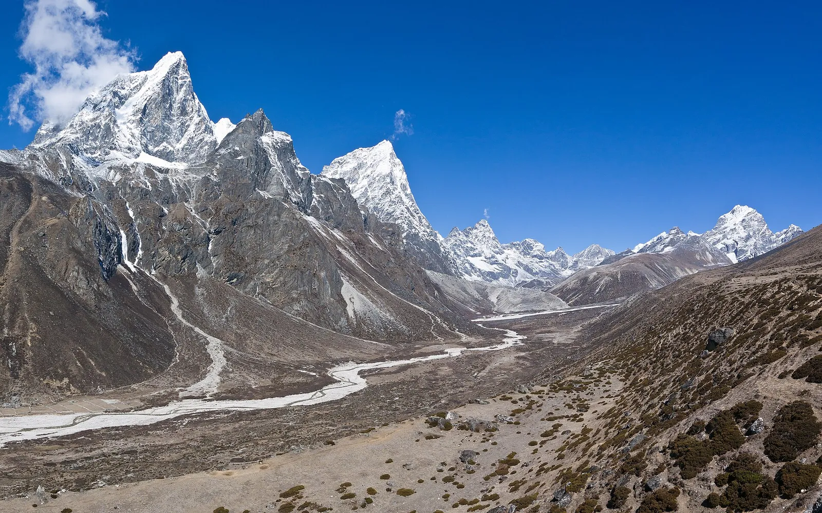 Široké údolí s větvící se řekou pod zasněženými vrcholy nad Pheriche v Khumbu