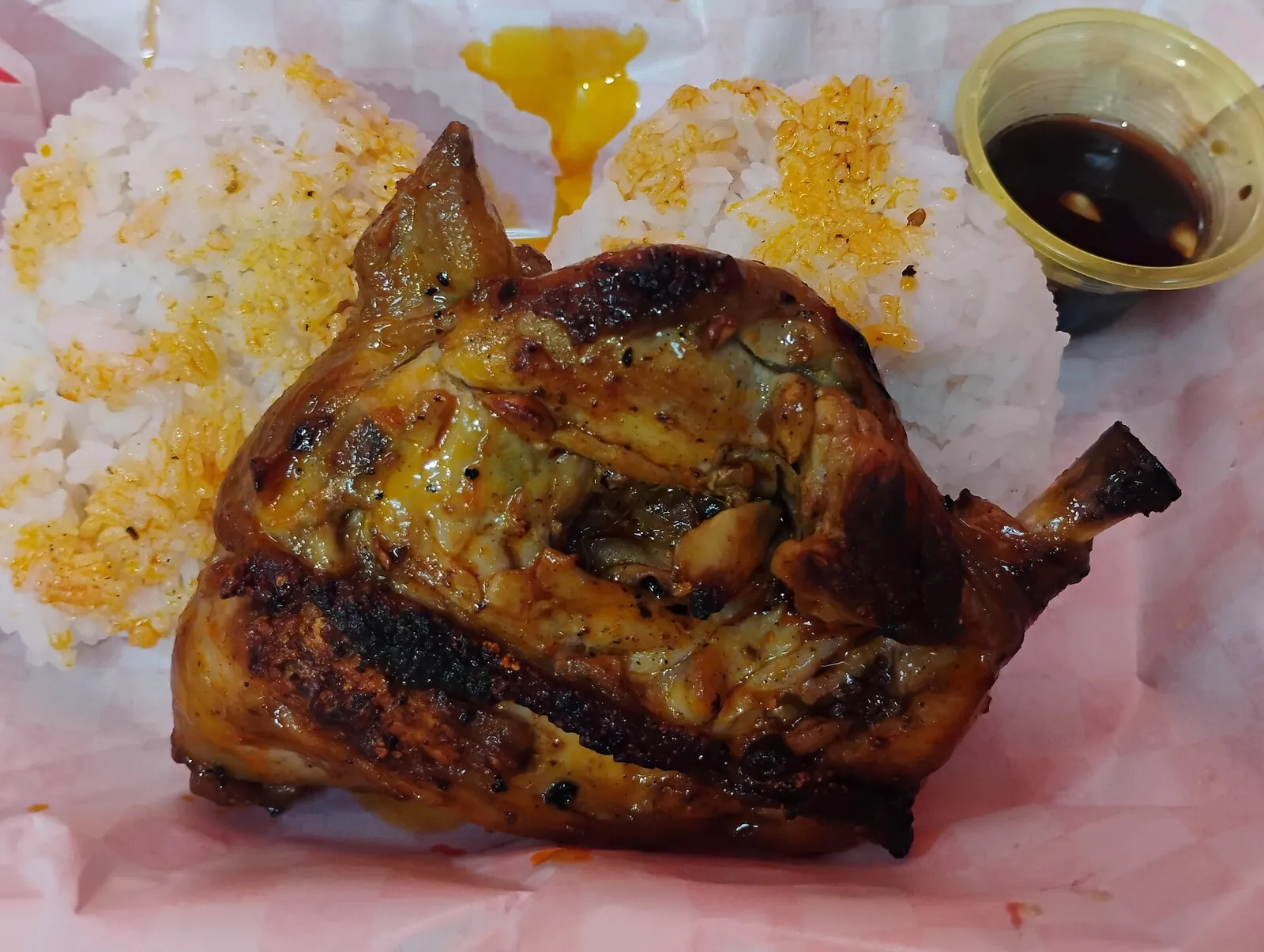 Chicken inasal with rice and dipping sauce on a plate