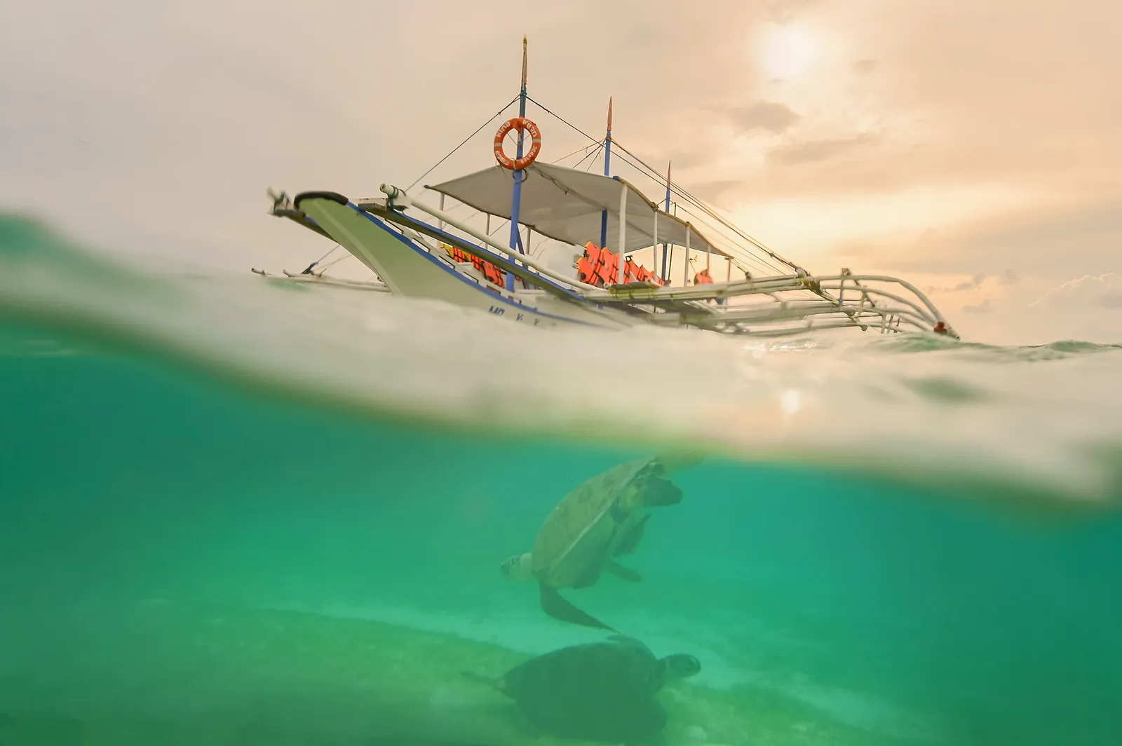 A sea turtle below the waterline and a banca boat above it at Onok Island