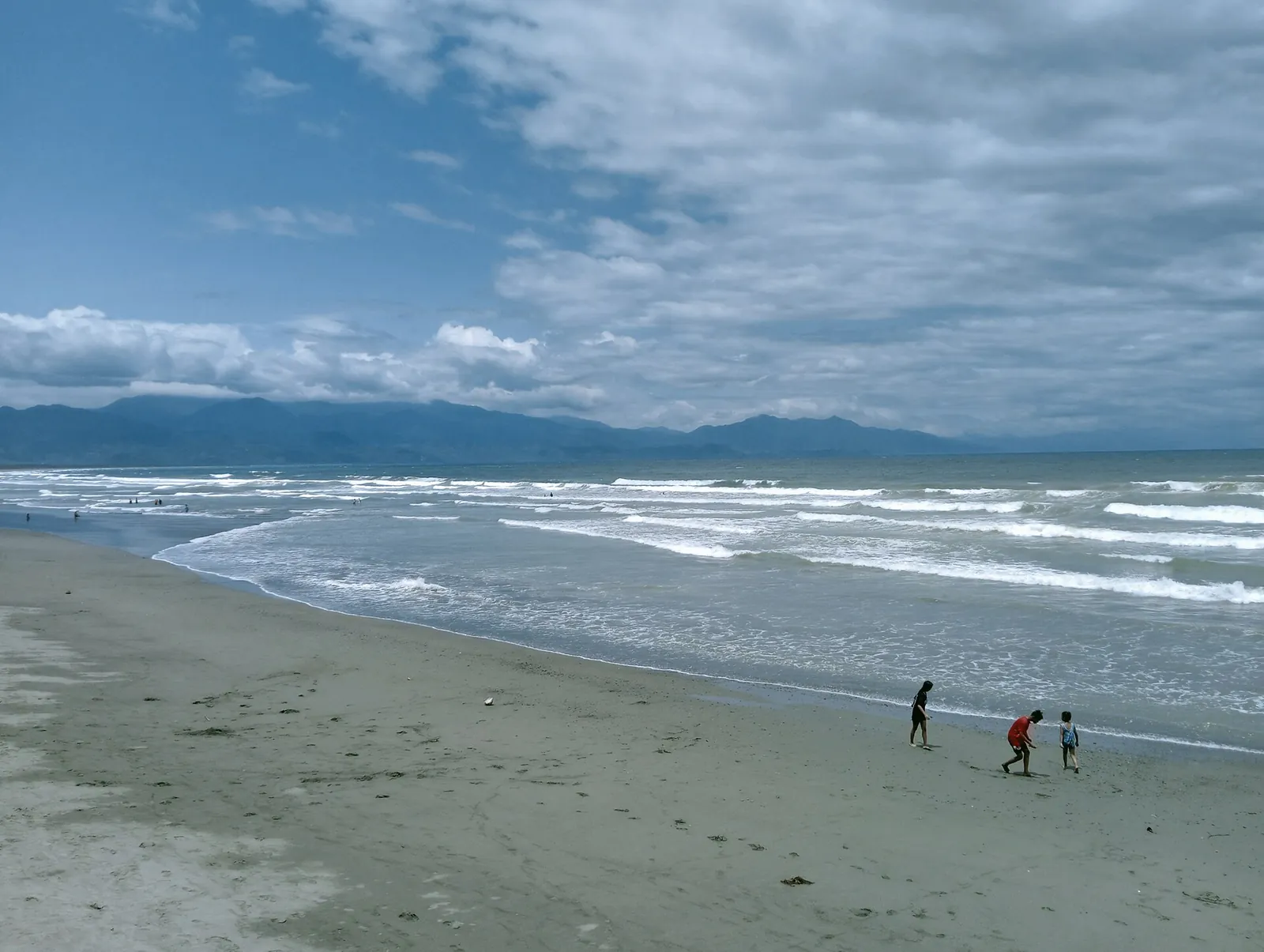 Waves and broad sandy shoreline at Sabang Beach in Baler