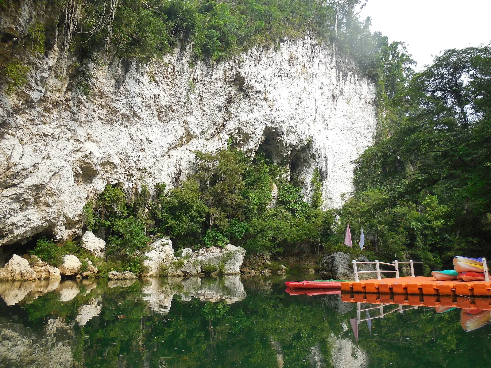 Limestone Panhulugan cliff and orange boat quay on the river in Basey