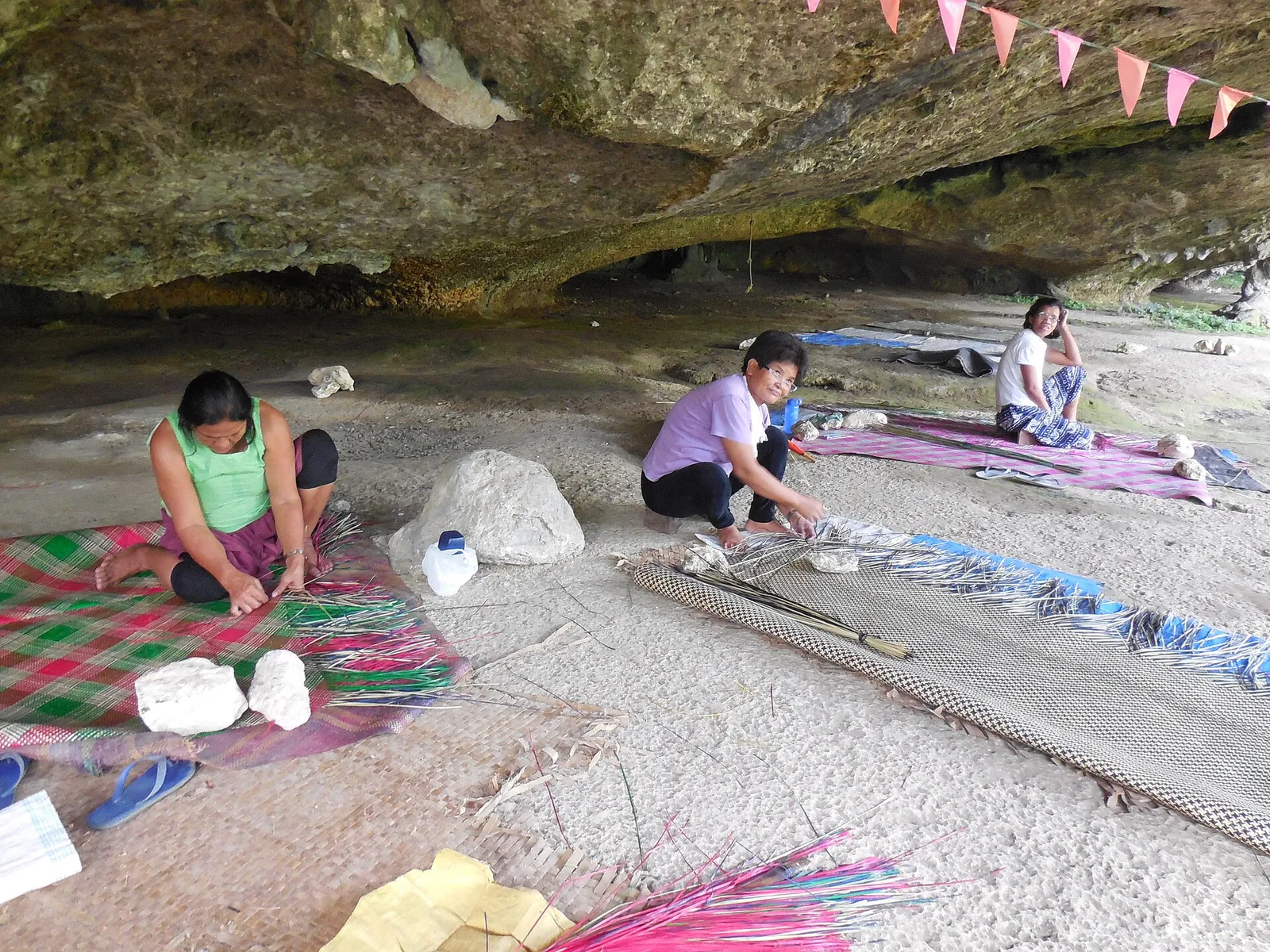 Women weaving colourful banig mats inside Saob Cave in Basey