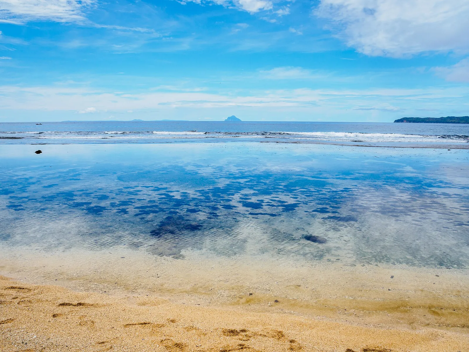 Clear shallow water and sandy shoreline at Maydangeb Beach in Batanes
