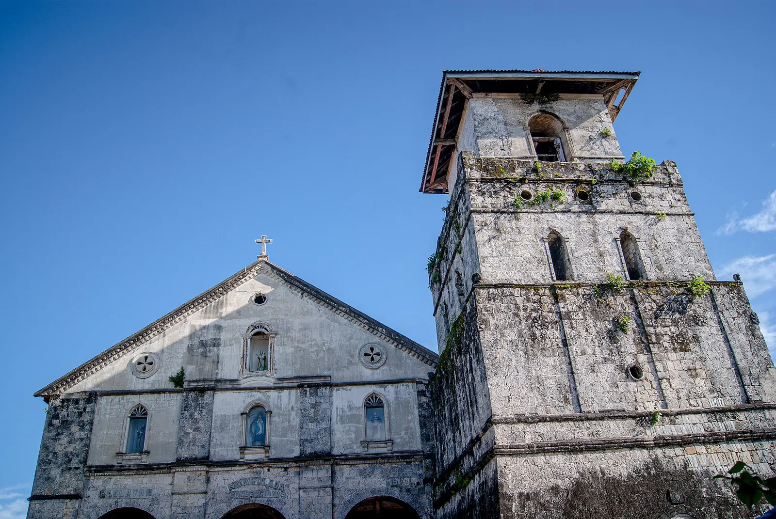 Stone facade and bell tower of Baclayon Church against a blue sky
