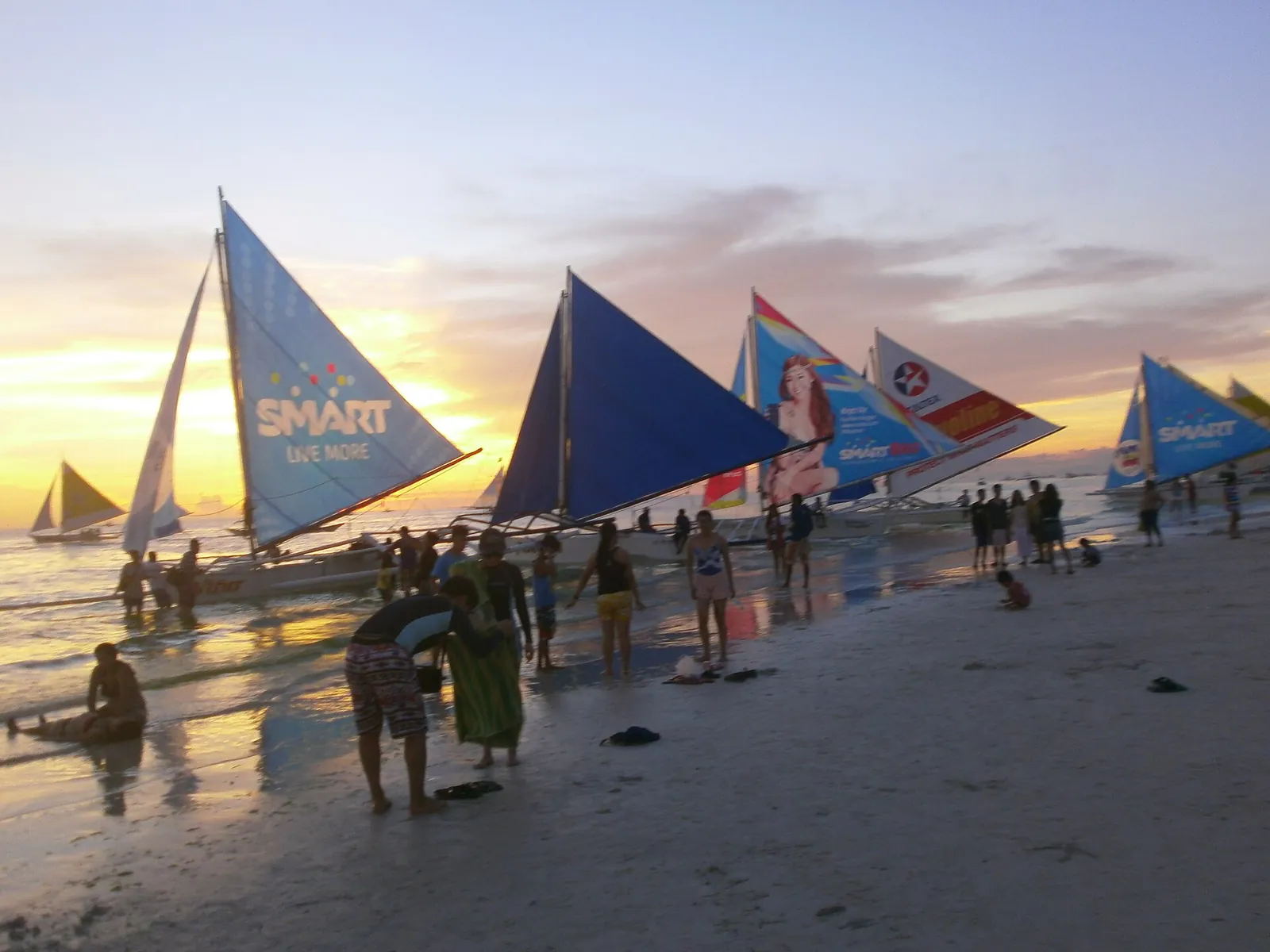 Paraw sailboats and visitors along White Beach on Boracay