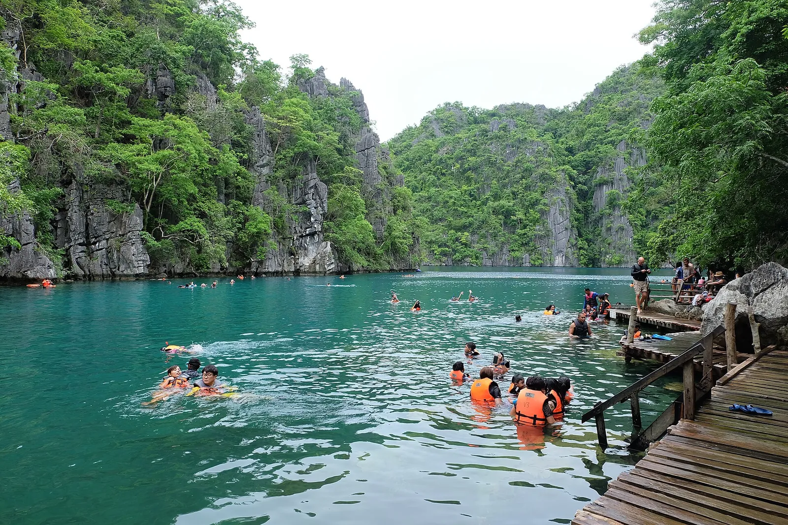 Visitors wearing life jackets beside a wooden walkway on Kayangan Lake