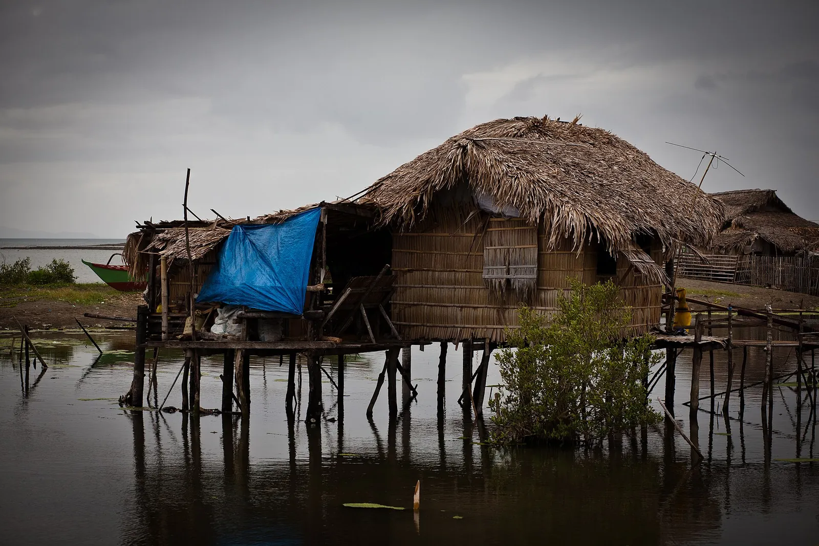 Thatched wooden house raised above coastal water at Donsol
